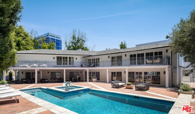 back of property featuring a patio and a pool with hot tub