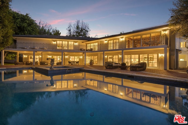 back house at dusk featuring a patio