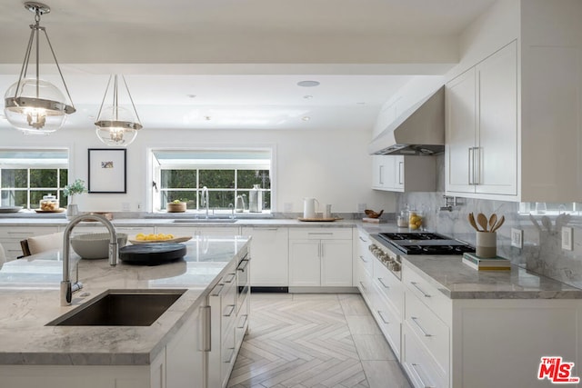 kitchen with sink, light stone counters, pendant lighting, extractor fan, and white cabinets