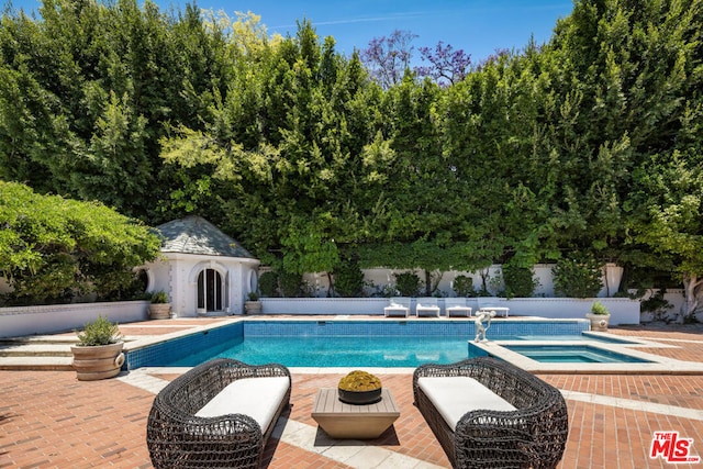 view of pool with an in ground hot tub, an outbuilding, and a patio area