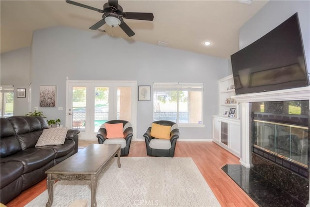 living room featuring ceiling fan, a fireplace, lofted ceiling, and light wood-type flooring