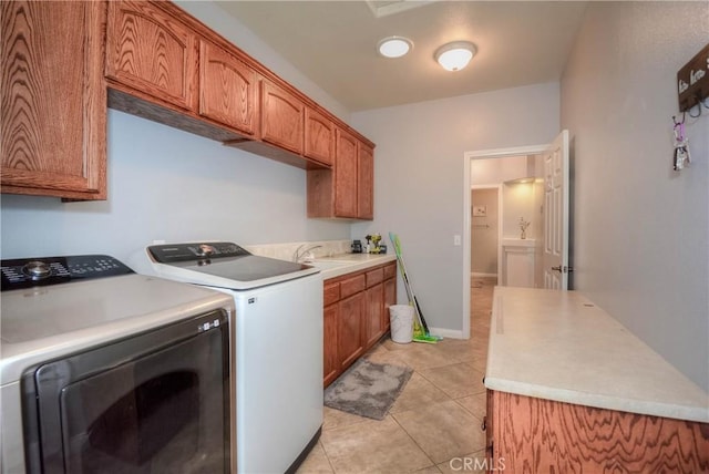 clothes washing area featuring washing machine and clothes dryer, sink, light tile patterned floors, and cabinets