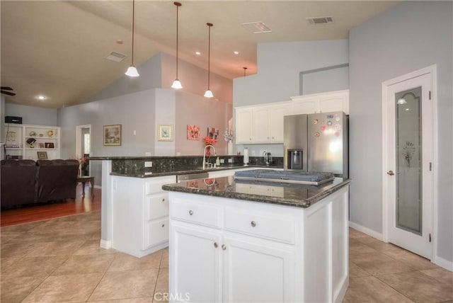 kitchen featuring appliances with stainless steel finishes, a kitchen island, high vaulted ceiling, white cabinetry, and hanging light fixtures