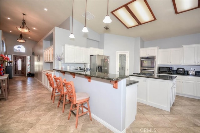 kitchen with white cabinetry, stainless steel appliances, high vaulted ceiling, pendant lighting, and a kitchen island