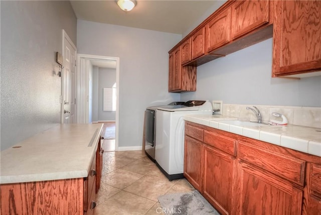 laundry area featuring cabinets, light tile patterned floors, sink, and washing machine and clothes dryer