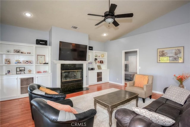 living room featuring ceiling fan, light wood-type flooring, lofted ceiling, and a high end fireplace