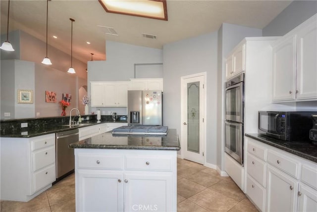 kitchen with white cabinets, vaulted ceiling, stainless steel appliances, and a kitchen island