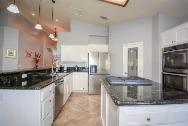 kitchen with white cabinets, pendant lighting, lofted ceiling, and appliances with stainless steel finishes