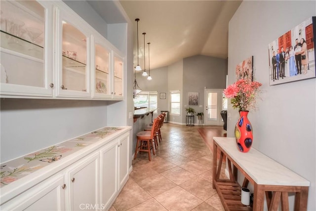 bar with white cabinets, light tile patterned flooring, hanging light fixtures, and vaulted ceiling