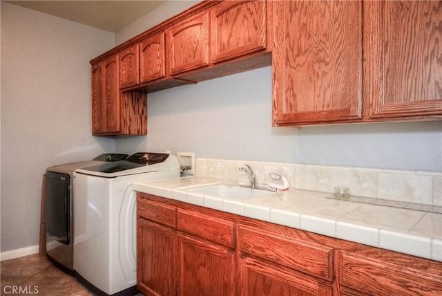 laundry area with separate washer and dryer, sink, cabinets, and dark tile patterned flooring