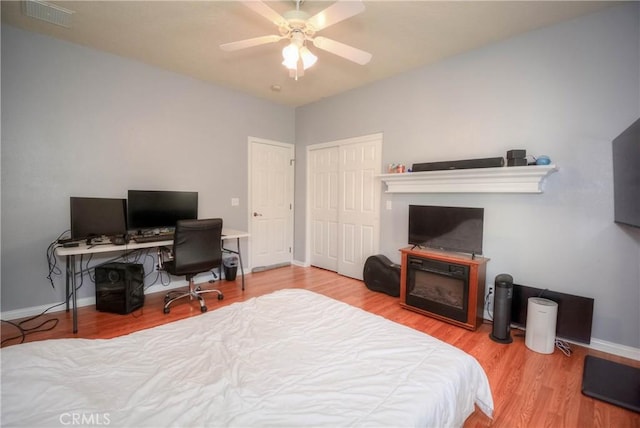 bedroom with hardwood / wood-style floors, ceiling fan, and a fireplace