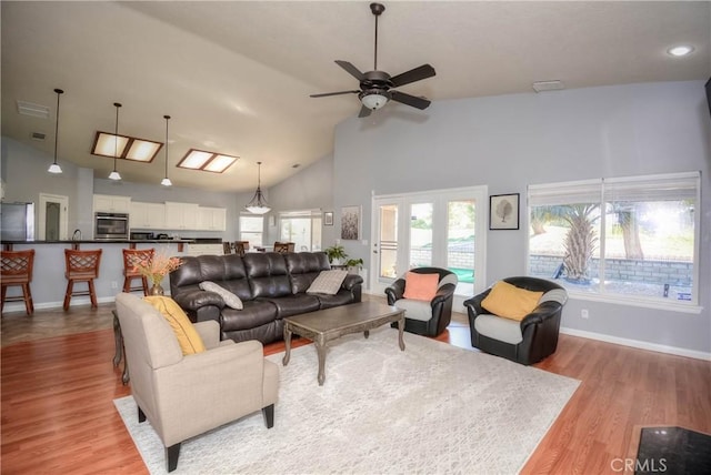 living room with ceiling fan, light hardwood / wood-style floors, high vaulted ceiling, and french doors