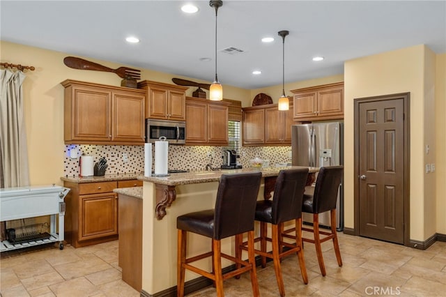 kitchen featuring pendant lighting, a center island, a breakfast bar area, light stone countertops, and stainless steel appliances