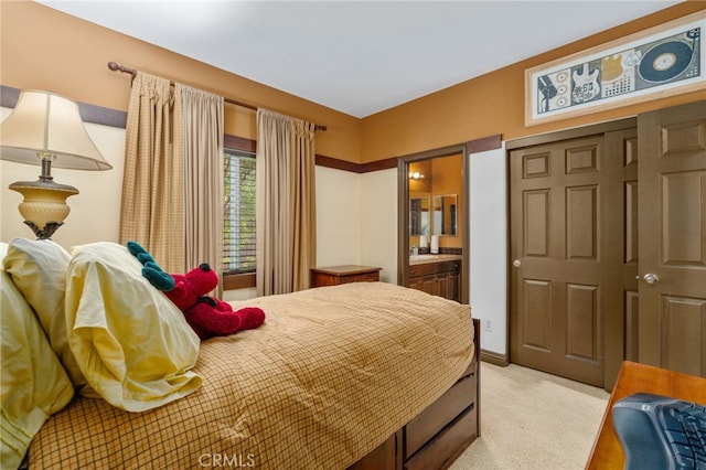 bedroom with ensuite bath and light colored carpet