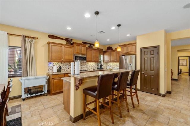 kitchen featuring light stone countertops, hanging light fixtures, stainless steel appliances, decorative backsplash, and a kitchen island