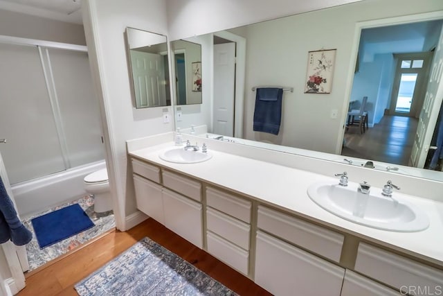 full bathroom featuring hardwood / wood-style floors, vanity, enclosed tub / shower combo, and toilet