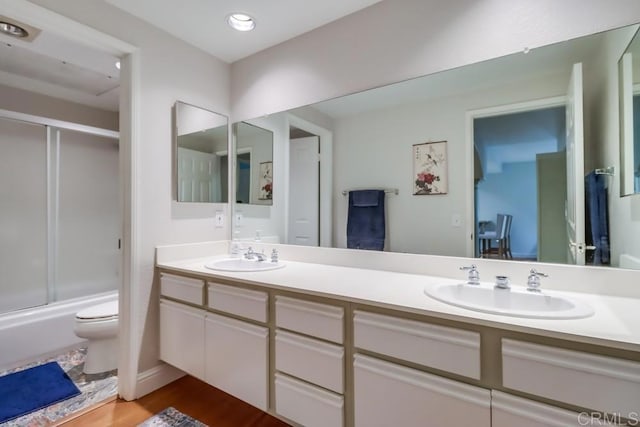 full bathroom featuring shower / bath combination with glass door, wood-type flooring, vanity, and toilet