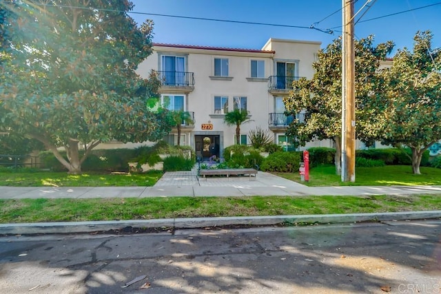 view of front of house with a balcony and a front lawn