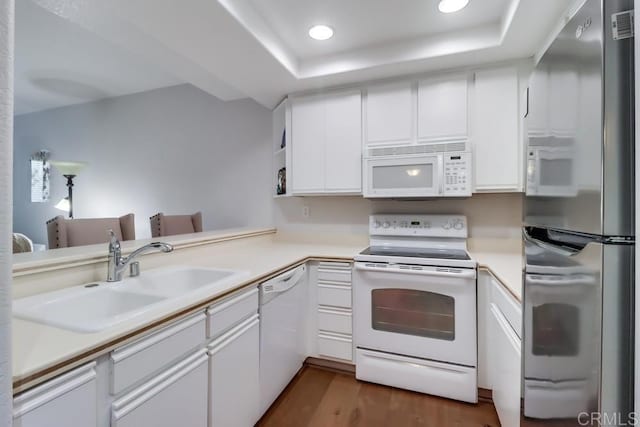 kitchen featuring white appliances, white cabinets, sink, dark hardwood / wood-style flooring, and kitchen peninsula