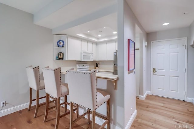 kitchen with kitchen peninsula, stainless steel fridge, stove, light hardwood / wood-style floors, and white cabinetry