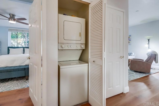 washroom featuring hardwood / wood-style flooring, ceiling fan, and stacked washing maching and dryer