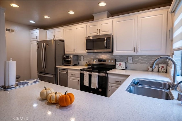 kitchen with decorative backsplash, white cabinetry, sink, and appliances with stainless steel finishes