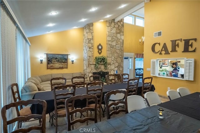 dining area with a fireplace, lofted ceiling with beams, and an inviting chandelier