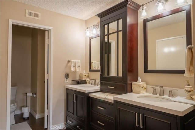 bathroom featuring vanity, toilet, and a textured ceiling