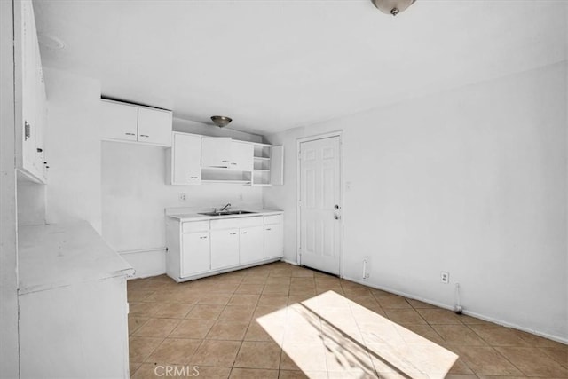 kitchen with white cabinets, light tile patterned floors, and sink