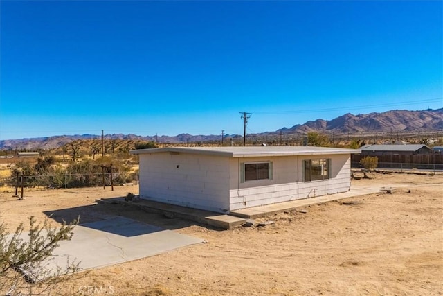 back of property with a mountain view and a patio area