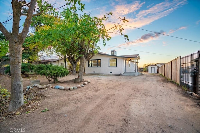 view of front of home featuring an outbuilding, dirt driveway, crawl space, fence, and a shed