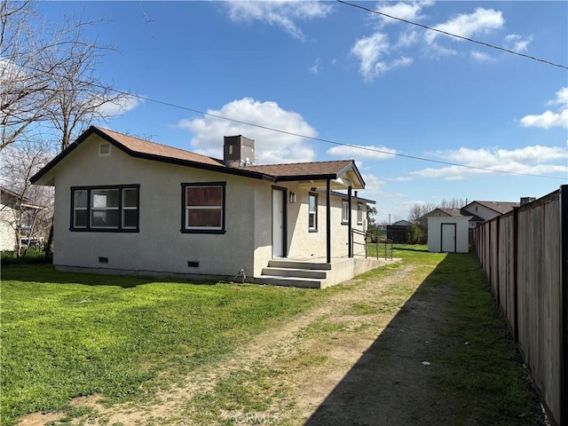 rear view of house featuring stucco siding, a storage shed, crawl space, fence, and an outdoor structure