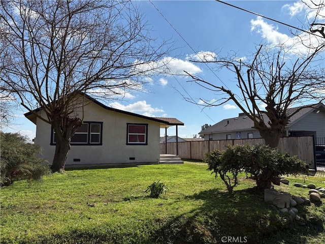 back of property featuring crawl space, a yard, fence, and stucco siding