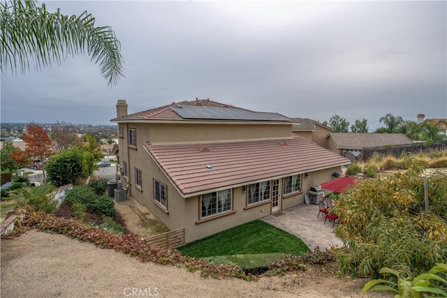 back of house with solar panels, a patio, and central AC