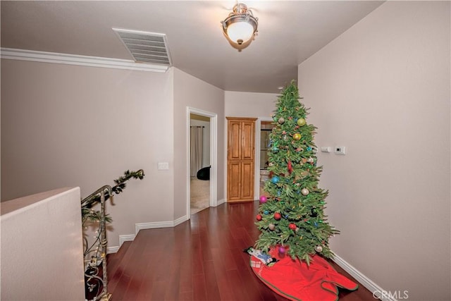 hallway with dark hardwood / wood-style floors and crown molding