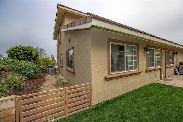 view of side of home with cooling unit and a yard