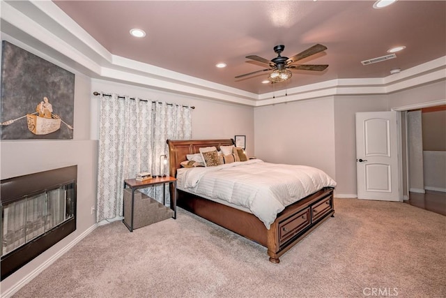 carpeted bedroom with ceiling fan and a tray ceiling