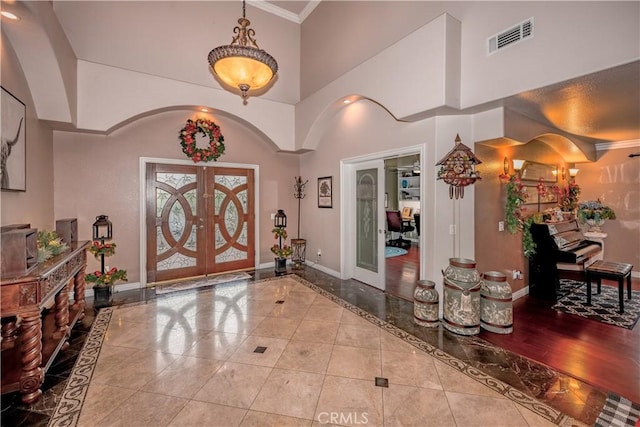 tiled entryway with french doors, crown molding, and a high ceiling