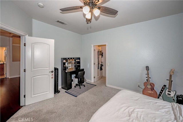 carpeted bedroom with a walk in closet and ceiling fan