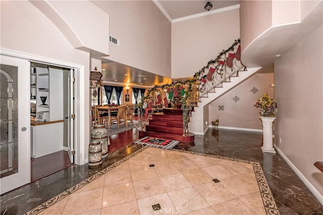 foyer entrance featuring ornamental molding and a towering ceiling