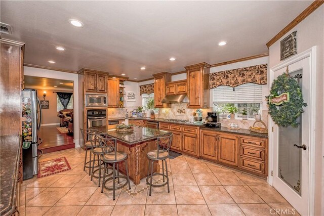 kitchen featuring light tile patterned flooring, a kitchen breakfast bar, tasteful backsplash, a kitchen island, and stainless steel appliances