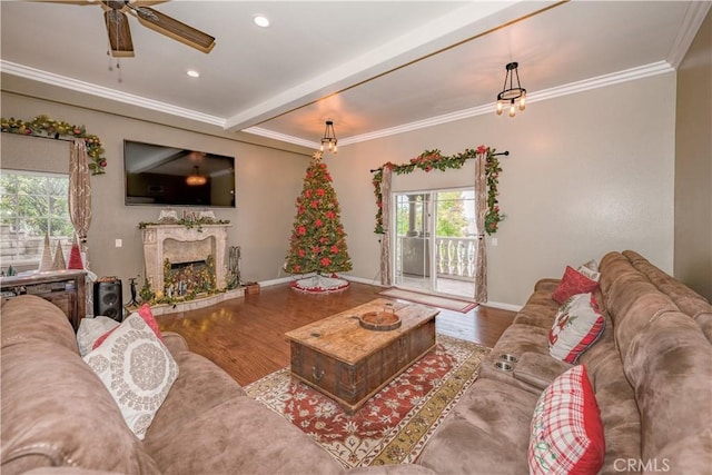 living room with hardwood / wood-style flooring, ceiling fan, ornamental molding, and a fireplace