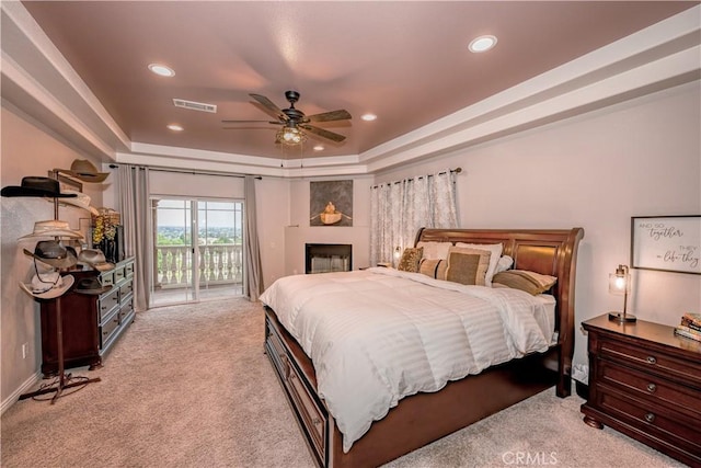 bedroom with a raised ceiling, access to exterior, ceiling fan, and light carpet