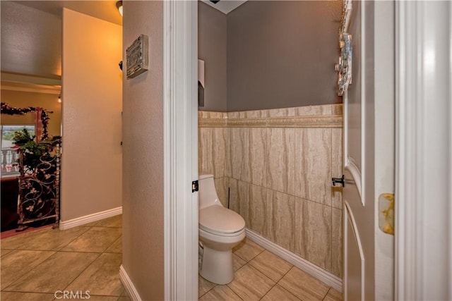 bathroom with tile patterned flooring, toilet, and tile walls