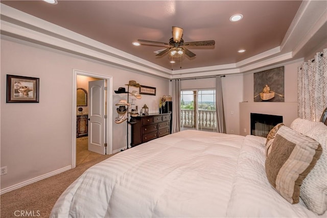 bedroom with access to exterior, light colored carpet, ceiling fan, and a tray ceiling