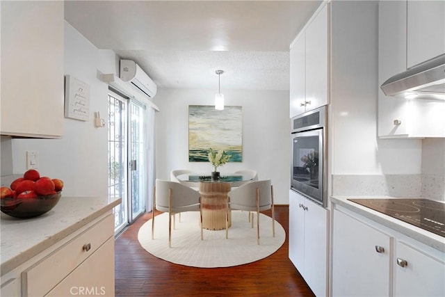 kitchen with white cabinetry, a wall unit AC, stainless steel oven, dark hardwood / wood-style flooring, and hanging light fixtures