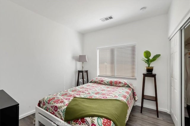 bedroom with dark wood-type flooring and a closet