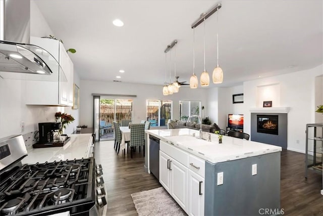 kitchen with wall chimney range hood, appliances with stainless steel finishes, a kitchen island, dark hardwood / wood-style flooring, and white cabinetry