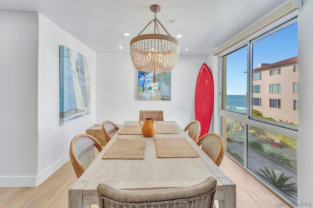 dining area featuring an inviting chandelier, light hardwood / wood-style flooring, and a water view