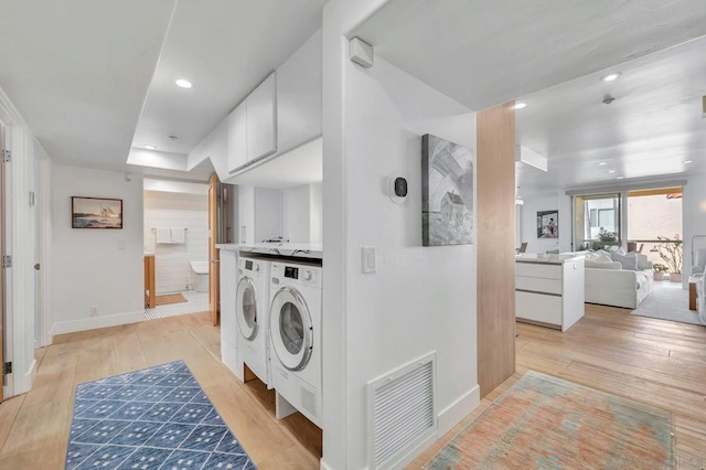 washroom with light hardwood / wood-style floors and washer and clothes dryer